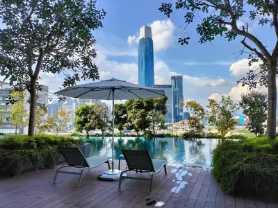a patio with two chairs and an umbrella next to a pond at KL City Central TRX 3 Bedrooms 2 Baths & Balcony in Kuala Lumpur