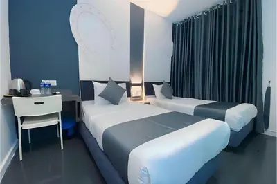 a hotel room with two beds and a desk and a desk at Hotel Pollodium Chinatown KL in Kuala Lumpur