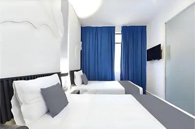 a hotel room with two beds and a mirror at Hotel Pollodium Chinatown KL in Kuala Lumpur