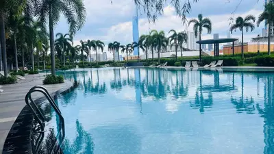 a swimming pool with palm trees in a city at TRION KL Premier Residence in Kuala Lumpur