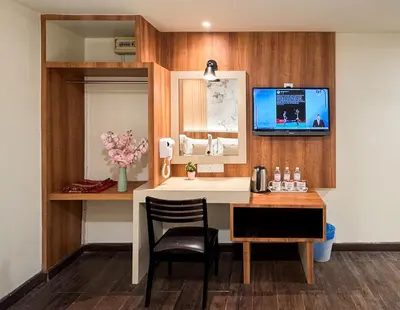 a room with a desk and a tv on a wall at Swiss Hotel at City Centre in Kuala Lumpur