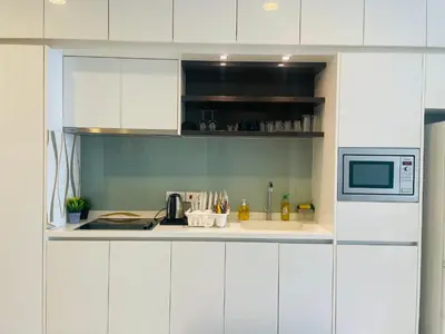 a kitchen with white cabinets and a microwave at The Platinum Suite KL in Kuala Lumpur