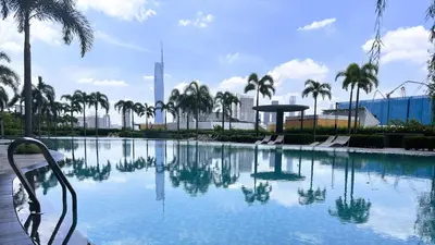 a large swimming pool with palm trees in a city at Couple Studio Suite B29 03A Trion KL in Kuala Lumpur