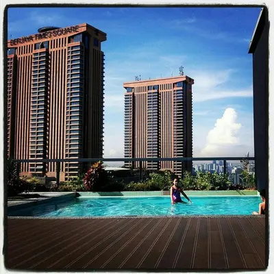 a child in a swimming pool with tall buildings at Bintang Fairlane Residence, KLCC & City View with Bathtub - 2B1R in Kuala Lumpur