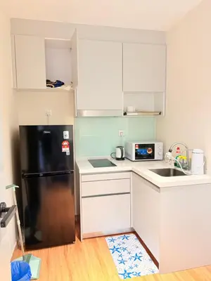 a kitchen with a black refrigerator and white cabinets at The Sentral Nook KL Sentral By Riveria city in Kuala Lumpur