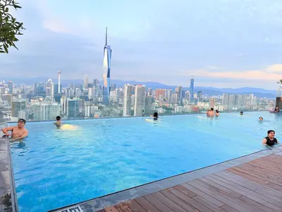 a group of people in a swimming pool with a city in the background at The Sentral Nook KL Sentral By Riveria city in Kuala Lumpur