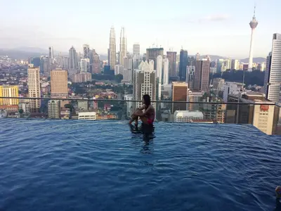 a woman sitting in a infinity pool on top of a building at Amazing KLCC View @ Regalia Residence in Kuala Lumpur