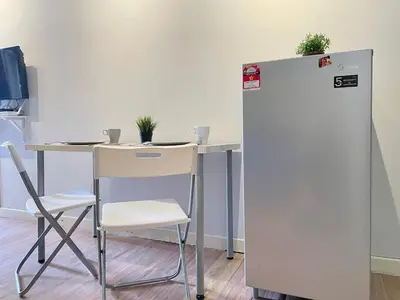 a table and chair next to a white refrigerator at Holiday Place Residence Kuala Lumpur in Kuala Lumpur