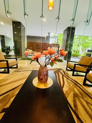 a vase with orange flowers on a table in a room at M City by Celestia Suites in Kuala Lumpur