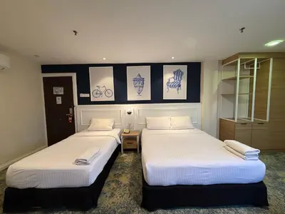 two beds in a hotel room with white sheets at Asto Hotel Kuala Lumpur in Kuala Lumpur