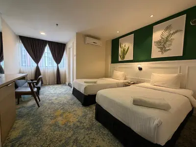 a hotel room with two beds and a desk at Asto Hotel Kuala Lumpur in Kuala Lumpur