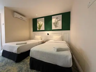 two beds in a hotel room with green walls at Asto Hotel Kuala Lumpur in Kuala Lumpur