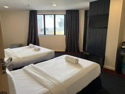 a hotel room with two beds and a television at Asto Hotel Kuala Lumpur in Kuala Lumpur