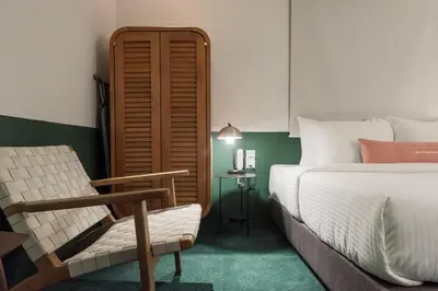 a bedroom with a bed and a chair and a table at Swing & Pillows - Kentomen Hotel, Bamboo Hills in Kuala Lumpur
