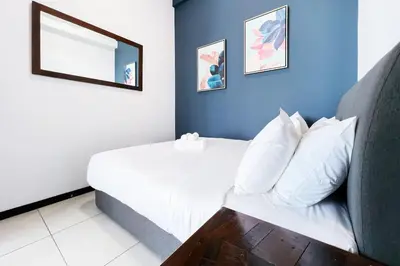 a bedroom with a white bed with two pictures on the wall at Contemporary Apartment KL with 3 Bedrooms in Kuala Lumpur