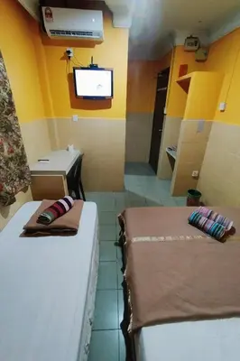 two beds in a room with a tv on the wall at 98 Inn BilikXpert at Chow Kit in Kuala Lumpur