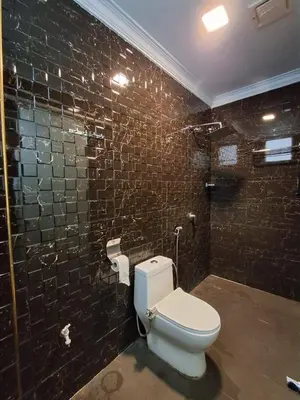 a bathroom with a toilet and a black tiled wall at Hotel AL Amin in Kuala Lumpur