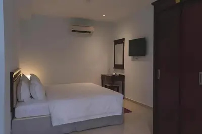 a bedroom with a white bed and a television at Hotel AL Amin in Kuala Lumpur