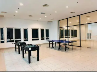 two ping pong tables in a room with windows at Taragon Puteri Bintang KLCC View Studio Apartment in Kuala Lumpur