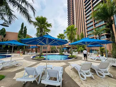 a pool with blue umbrellas and white chairs at City view Service Residence At Times Square kL in Kuala Lumpur