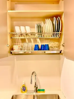 a kitchen sink with plates and glasses on a shelf at Dorsett Luxury KLCC by IHG in Kuala Lumpur