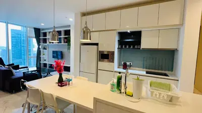 a kitchen with white cabinets and a table with chairs at The Platinum KLCC By Elegant Suites in Kuala Lumpur
