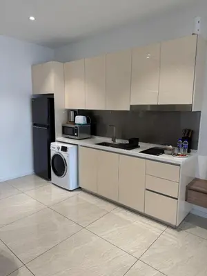 a kitchen with white cabinets and a washer and dryer at Quill Residence - Sky Glass Condo by Azmila in Kuala Lumpur