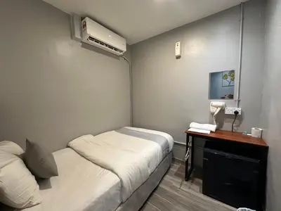 a small room with two beds and a desk with a phone at SS Grey House Bukit Bintang KL in Kuala Lumpur