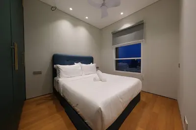 a bedroom with a bed with a blue headboard and a window at 3R2B SkySuites Next to KLCC Twin Tower High Floor in Kuala Lumpur