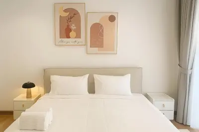 a bedroom with a white bed and two pictures on the wall at Quill Residences Klcc By AB in Kuala Lumpur