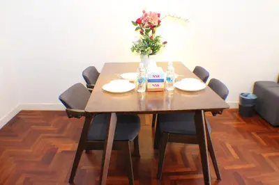 a wooden table with chairs and a vase of flowers at KLCC Sky Villa Suites The Mews in Kuala Lumpur