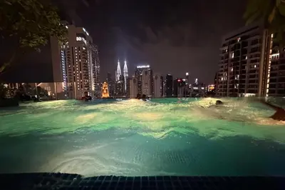 a large swimming pool with a city skyline at night at Majestic Residence KLCC By Flixhome in Kuala Lumpur