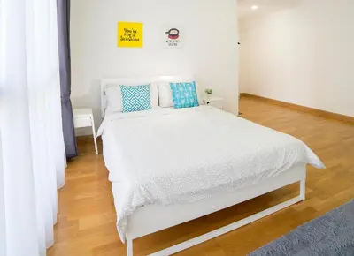 a bedroom with a white bed with blue pillows at Karaoke Party Penthouse at KL Gateway by Cobnb in Kuala Lumpur