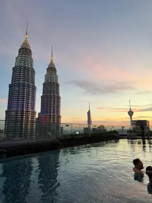 two people swimming in a pool with a city skyline at Star Residences KLCC by Nexus 3A in Kuala Lumpur