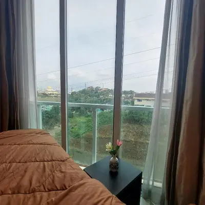 a bedroom with a large window with a vase with flowers on a table at Damas Plaza-Hartamas in Kuala Lumpur