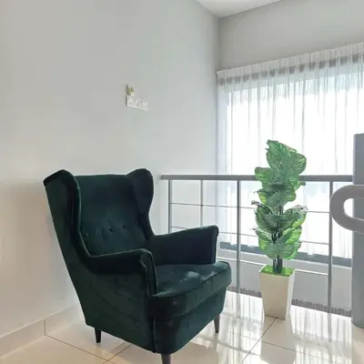 a green chair in a living room with a potted plant at 3 Tower Ampang Suite in Kuala Lumpur