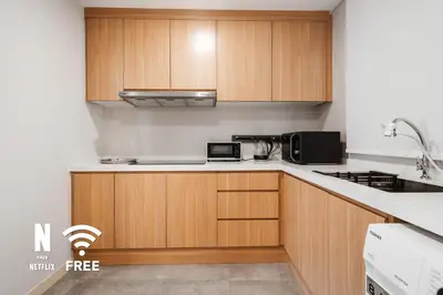 a kitchen with wooden cabinets and a microwave at Mont Kiara Ooak Suite Sunway 163 with Bathtub 2 Bed in Kuala Lumpur