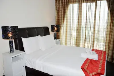 a bedroom with a large white bed with two lamps at Taragon Residences in Kuala Lumpur