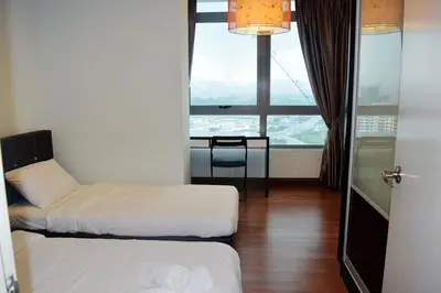 a room with two beds and a table and a window at Taragon Residences in Kuala Lumpur