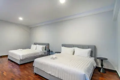 two beds in a room with white walls and wood floors at Embassy Villa by COBNB, Top Floor Unit at Ampang Hilir in Kuala Lumpur