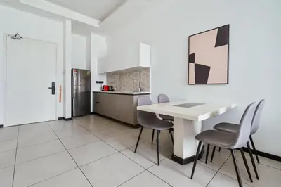a white kitchen with a white table and chairs at Blueground Kuala Lumpur pool nr KL Bird Park KUL-3 in Kuala Lumpur