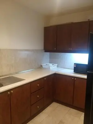 a kitchen with wooden cabinets and a counter top at Happy holiday suites at times square KL in Kuala Lumpur