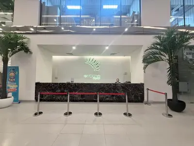a lobby with a counter and two palm trees at Summer popular suites kl Bukit Bintang in Kuala Lumpur