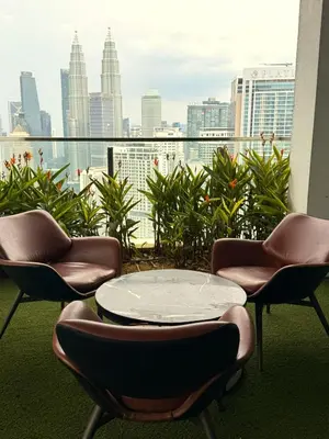 a balcony with chairs and a table and a view of the city at Lucky Suites KLCC By LUXE Infinitum in Kuala Lumpur
