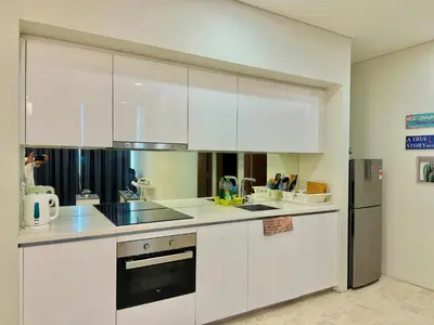 a kitchen with white cabinets and a refrigerator at Sky Suites KLCC By Stay Happy in Kuala Lumpur