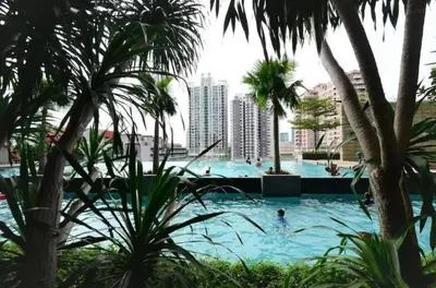 a swimming pool with palm trees and people in it at Putra Suite KL in Kuala Lumpur