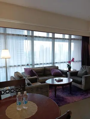 a living room with couches and tables and windows at Crown Suits At Times Square in Kuala Lumpur