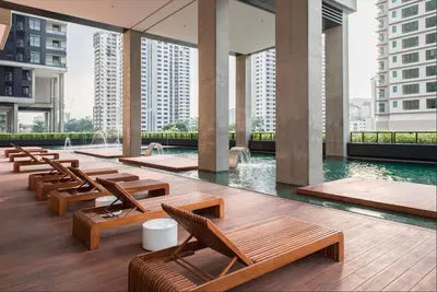 a hotel lobby with wooden chairs and a pool at netflix&chill Arcoris Soho 2R1B Mont Kiara in Kuala Lumpur