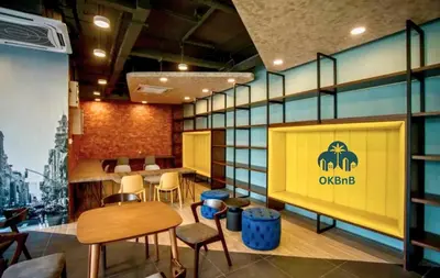 a restaurant with chairs and a yellow sign on the wall at Neu Suites by OKBnB in Kuala Lumpur