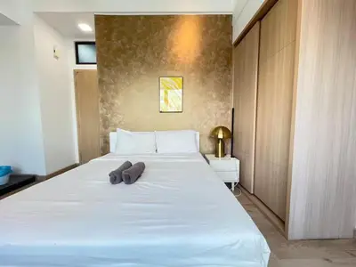 a large white bed with two brown slippers on it at The Colony By Infinitum D in Kuala Lumpur